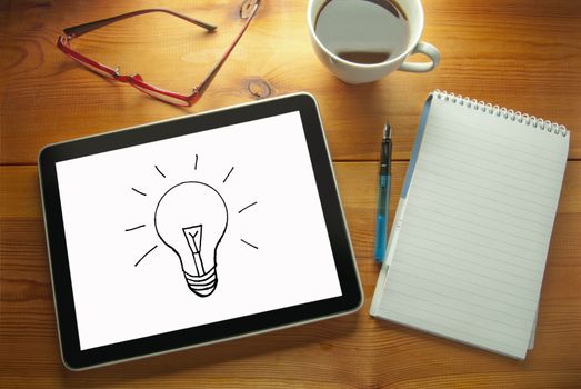 Work desk with idea bulb symbol drawn on a computer tablet 