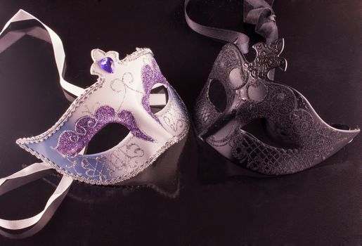 Venetian masks over a black reflecting background