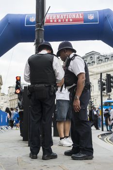 LONDON, UK - SEPTEMBER 27: British policemen standing next to inflatable NFL arch. September 27, 2014 in London. Regent street was closed to traffic to host NFL related games and events.
