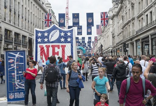 LONDON UK - SEPTEMBER 27: Crowded Regent street with NFL inflatable banners and flags hanging above. September 27 2014 in London. The street was closed to traffic to host NFL related games and events.