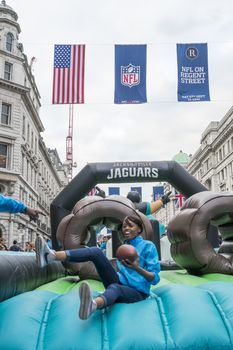 LONDON UK - SEPTEMBER 27: Girl sliding through Jacksonville Jaguars structure in Regent street. September 27 2014 in London. The street was closed to traffic to host NFL related games and events.