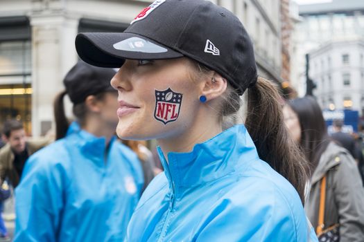 LONDON UK - SEPTEMBER 27: Profile portrait of beautiful girl with NFL logo painted on cheek. September 27 2014 in London. The street was closed to traffic to host NFL related games and events.