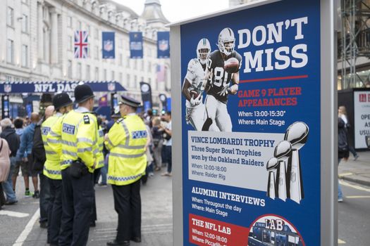 LONDON, UK - SEPTEMBER 27: NFL billboard with British policemen standing in the background. September 27, 2014 in London. Regent street was closed to traffic to host NFL related games and events.