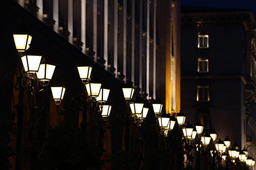 row of illuminated lampposts by night
