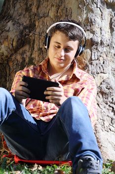 Teenager sitting in park with tablet pc