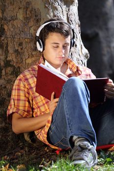 Teenager reading book outdoor in park