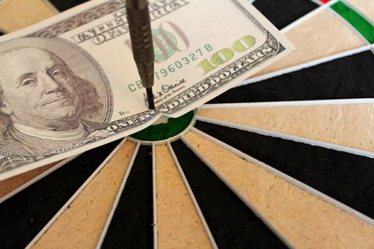 hundred dollar bill in the bullseye of a dart board