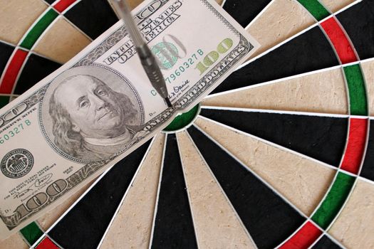 hundred dollar bill in the bullseye of a dart board