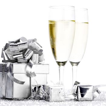 Glasses of champagne and silver gifts isolated on white