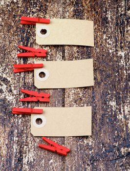 Decorative Paper Tags with Red Wooden Сlothespins In a Row on Wooden background