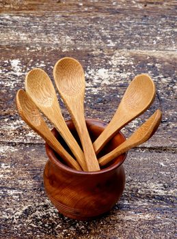 Five Small Wooden Spoons in Pot isolated on Rustic Wooden background