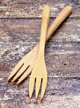 Two Small Wooden Forks isolated on Textured Wooden background. Focus on Foreground