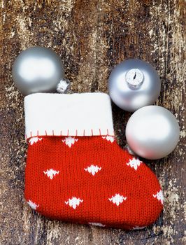 Christmas Decoration with Handmade Knitted Sock and Pastel Colored Baubles on Textured Wooden background. Top View