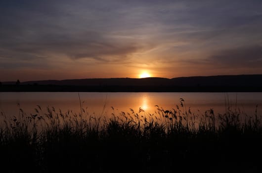 Sunset behind the Blue Mountains and reflections on Duralia Lake and silhouette of reeds at Penrith NSW Australia