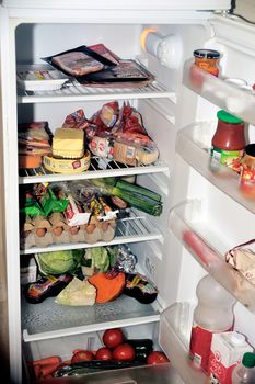 Open refrigerator containing food products each day as eggs, butter, cheese, sausage, meat and vegetables