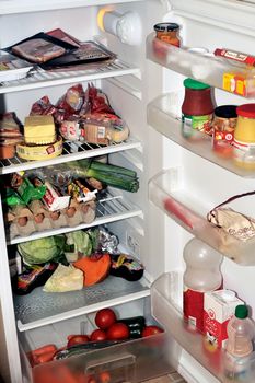 Open refrigerator containing food products each day as eggs, butter, cheese, sausage, meat and vegetables