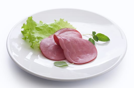 Two pieces of beef sausages cuts with green lettuce on the white plate