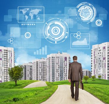Businessman in suit walking along road through green hills. Rear view. City of tall buildings in background. Charts and other virtual items in sky. Business concept