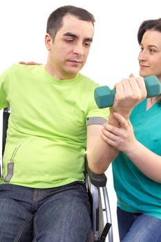 Physical therapist works with patient in lifting hands weights. young adult in wheelchair.