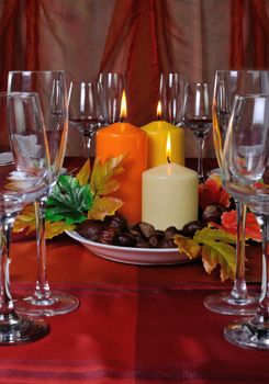Candles as part of table setting with chestnuts in the autumn leaves