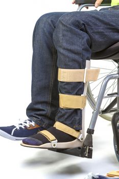 Orthopedist puts orthosis to patient in wheelchair with disabilities