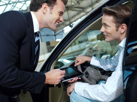 Car salesperson explaining car features to customer 