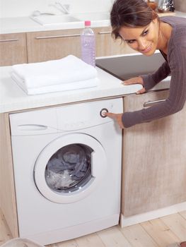 smiling female pressing a button on her washing machine 