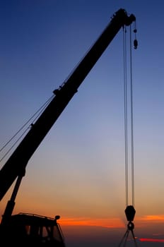 Silhouette crane working at port with sunset sky background