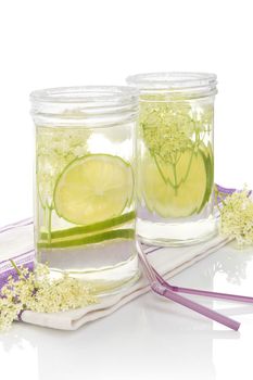 Elderberry lemonade. Two glasses with elderberry lemonade with ice and lime slices isolated on white background.