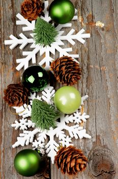 Arrangement of Little Christmas Trees, Green Baubles, Decorative Fir Cones and Snowflake Shapes In a Row on Rustic Wooden background