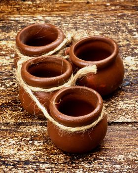 Four Small Empty Handmade Pottery Pots with Rope closeup on Textured Wooden background