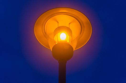 Illuminated old street lamp against the evening sky photographed.