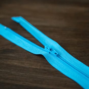 Blue clothing zipper on dark wood background