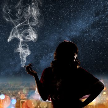 Silhouette of Asian christmas girl holding a cigar in the city night.