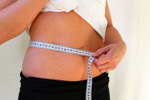 Young woman on a diet measuring her waist