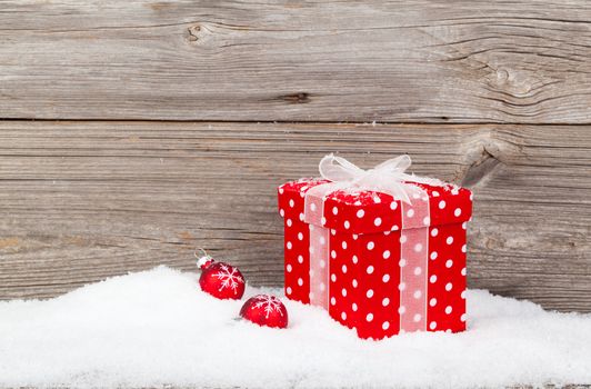 christmas red gift with snow, on wooden background