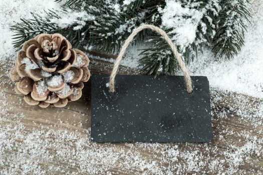 Black board of slate on old rustic wooden background, with snow