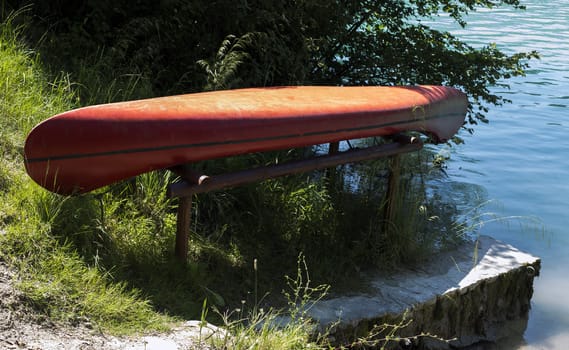 Red rowing boat placed upside down out of water.