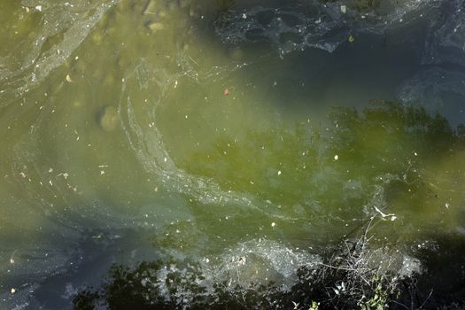 A photograph of polluted water, made from a bridge.