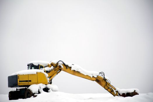Excavator being covered with a snow in winter.
