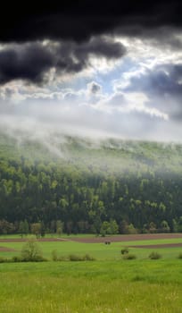 Nature panorama of a sky, clouds, mist, woods and land in one place.