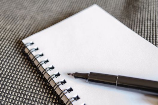 White notepad and ink pen on the wooden desk