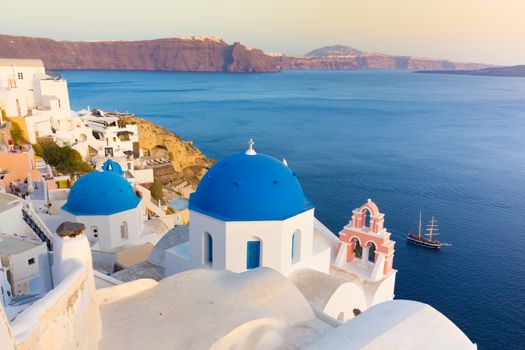 World famous traditional whitewashed chuches and houses of Oia village on Santorini island, Greece. Sunset light.