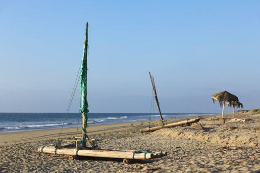Wooden raft with mast on the sandy beach of the popular small town of Mancora in Northern Peru (Selective Focus, Focus on the first raft) 
