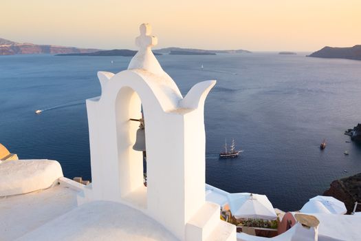 World famous traditional whitewashed chuche of Oia village on Santorini island, Greece. Sunset light.