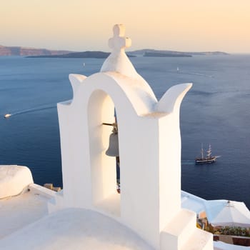 World famous traditional whitewashed chuche of Oia village on Santorini island, Greece. Sunset light.