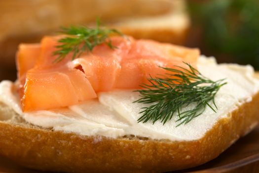 Canape of smoked salmon and cream cheese on wholewheat bun garnished with dill (Selective Focus, Focus on the front of the dill on the right)