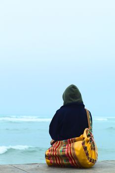 A person sitting on the coast and watching the sea on the shore of  Lima, Peru in winter