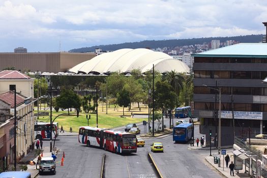 QUITO, ECUADOR - AUGUST 6, 2014: Unidentified people on the Gran Colombia Avenue with the Parque del Arbolito and the Casa de la Cultura Ecuatoriana in the back on August 6, 2014 in Quito, Ecuador 