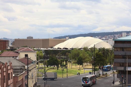 QUITO, ECUADOR - AUGUST 6, 2014: Unidentified people on the Gran Colombia Avenue with the Parque del Arbolito and the Casa de la Cultura Ecuatoriana in the back on August 6, 2014 in Quito, Ecuador 